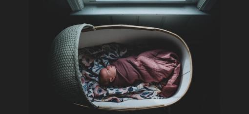 Swaddled baby in a bassinet