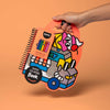 Hand holding a colorful packaging of a coloring book and crayons on an orange background