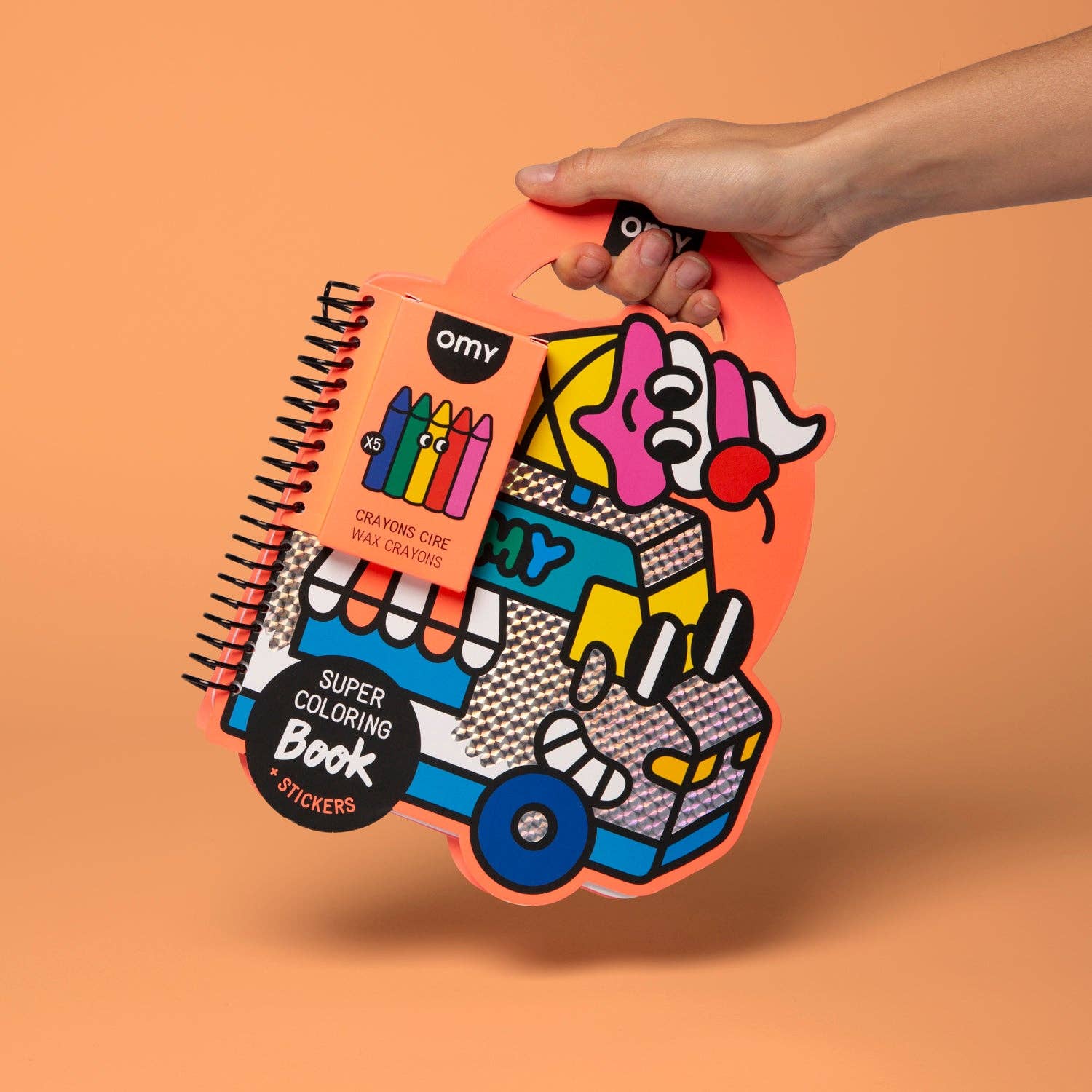 Hand holding a colorful packaging of a coloring book and crayons on an orange background