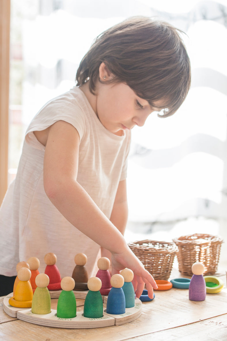 A kid standing, playing with the perpetual calendar and 12 ring set