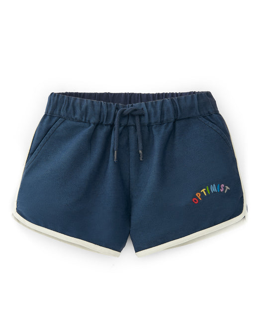 A flatlay image of a blue pair of track shorts with "be happy" embroidered on one leg